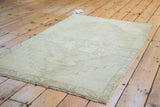 Distressed Oushak rug texture with subtle geometric medallion and serrated border.