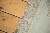 Worn fringe and geometric pattern along the edge of a platinum-toned distressed Oushak rug.