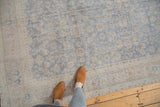 Distressed slate blue and neutral floral palmettes on a vintage Oushak rug.
