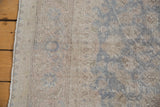 Distressed Oushak pile with time-softened slate blue and beige floral designs.