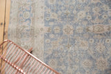 Distressed Oushak rug with faded floral palmettes in soft slate blue grey and beige.