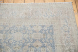 Textured distressed Oushak rug pile, showing faded slate blue and soft beige floral palmettes.