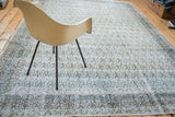 Distressed Khorassan rug corner with faded apricot paisley field and muted blue-green border.