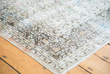Distressed Persian Khorassan rug corner with faded apricot, tan, and light blue patterns.