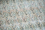 Distressed Khorassan rug's faded paisley pattern, revealing soft beige, peach, and blue tones.