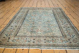 Distressed Oushak rug showing slate blue field and blush rose scrolling vine motif.