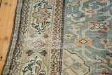 Distressed Oushak rug with blush rose scrolling vine on slate blue field and geometric border.