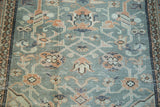 Textured slate blue distressed Oushak rug, blush rose scrolling vines, paneled border.