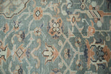 Textured detail of distressed Turkish Oushak rug with slate blue and blush rose scrolling vines.