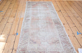 Geometric tribal pattern and distressed texture on the muted brick red Oushak runner.