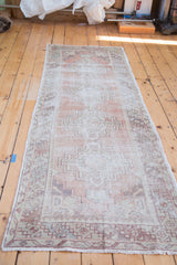 Vintage distressed Oushak runner, its geometric tribal medallions softly faded on a brick red field.