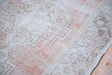 Distressed low pile and faded brick red field with geometric tribal patterns.