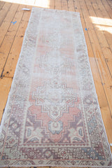 Distressed Oushak runner's grey corner spandrel with faded brick red and geometric tribal motifs.