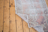 Distressed Oushak runner's faded geometric patterns, subtle color accents, and hand-knotted foundation.