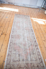 Distressed Oushak runner's geometric pattern in faded blush rose, beige, and charcoal.