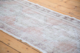 Distressed Turkish Oushak runner showing faded blush, beige, and silver geometric patterning.