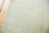 Close-up texture of vintage distressed Oushak rug pile with ivory, silver, and beige hues.