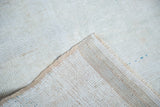 Distressed Oushak rug corner showing hand knotted back and soft cream pile with aqua.