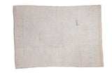 Aged foundation of a distressed 5x7 Oushak rug, revealing hand-knotted weave and faint blue details.