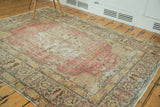 Distressed Oushak rug with faded red field, star medallion, gold, and charcoal green.