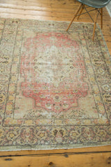 Distressed vintage Oushak rug detail, highlighting faded red field, gold, ivory, and charcoal green.