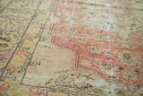 Distressed texture of vintage Oushak rug with intricate red, gold, ivory, and charcoal patterns.
