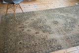 Distressed Oushak carpet with ornate geometric patterns in dusty beige, bronze, and charcoal.