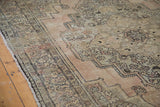 Distressed Oushak rug featuring muted geometric patterns in dusty beige, bronze, and charcoal.