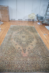 Distressed corner detail of hand-knotted Oushak carpet with beige, bronze, and charcoal geometric patterns.