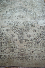 Textured geometric pattern of distressed Oushak carpet in dusty beige and charcoal.