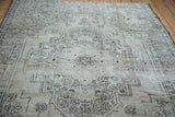 Distressed Oushak carpet's ornate geometric medallion with dusty beige, bronze, and charcoal.