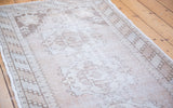 Faded ivory and beige distressed Oushak runner with textured pile and subtle medallion.