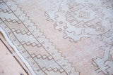 Muted dusty rose field and geometric border detail on a distressed Oushak runner.