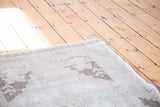 Faded ivory and beige tones with distressed geometric patterns on an Oushak runner.
