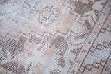 Distressed Oushak runner with faded dusty rose, ivory, and brown geometric pattern.