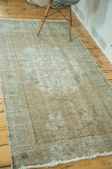 Distressed Oushak rug corner, showing worn pile texture, faint border, and short fringe.