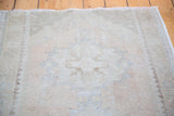 Distressed texture of an Oushak runner, with muted apricot, ivory, grey, and beige tones.