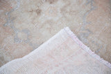 Distressed Oushak runner's light apricot pile texture, hand-knotted backing, and fringe.