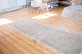 Distressed Oushak runner's soft texture and subtle curvilinear medallion in apricot, ivory.