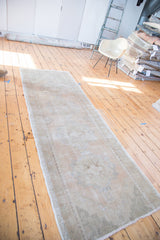 Decorative distressed Oushak runner, showcasing soft apricot, ivory, grey hues and fringe detail.