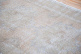 Distressed vintage Oushak runner displaying faded curvilinear motifs in light apricot and grey.