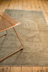 Distressed vintage Oushak rug showcasing faded neutral patterns and textured fringe.