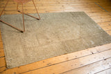 Distressed neutral pile and fringed corner of the vintage hand-knotted Oushak rug.