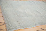 Distressed Oushak rug with low pile, featuring muted beige and silver rectilinear patterns.