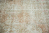 Distressed vintage Oushak rug texture, showing faded dusty rose and beige tones.