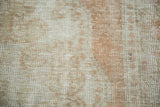 Faded pattern detail of a distressed Oushak rug, showing soft rose and beige pile.