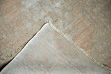 Distressed Oushak runner with faded apricot pile, showing hand-knotted foundation and fringe.