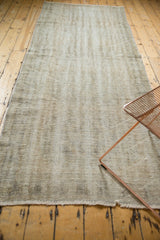 Distressed Oushak rug texture with finely shorn pile and short fringed edge.