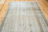 Distressed texture of a Turkish Oushak rug pile with soft apricot and light white tones.