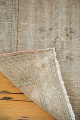 Hand-knotted Oushak rug corner folded, revealing the woven foundation and distressed light-toned pile.